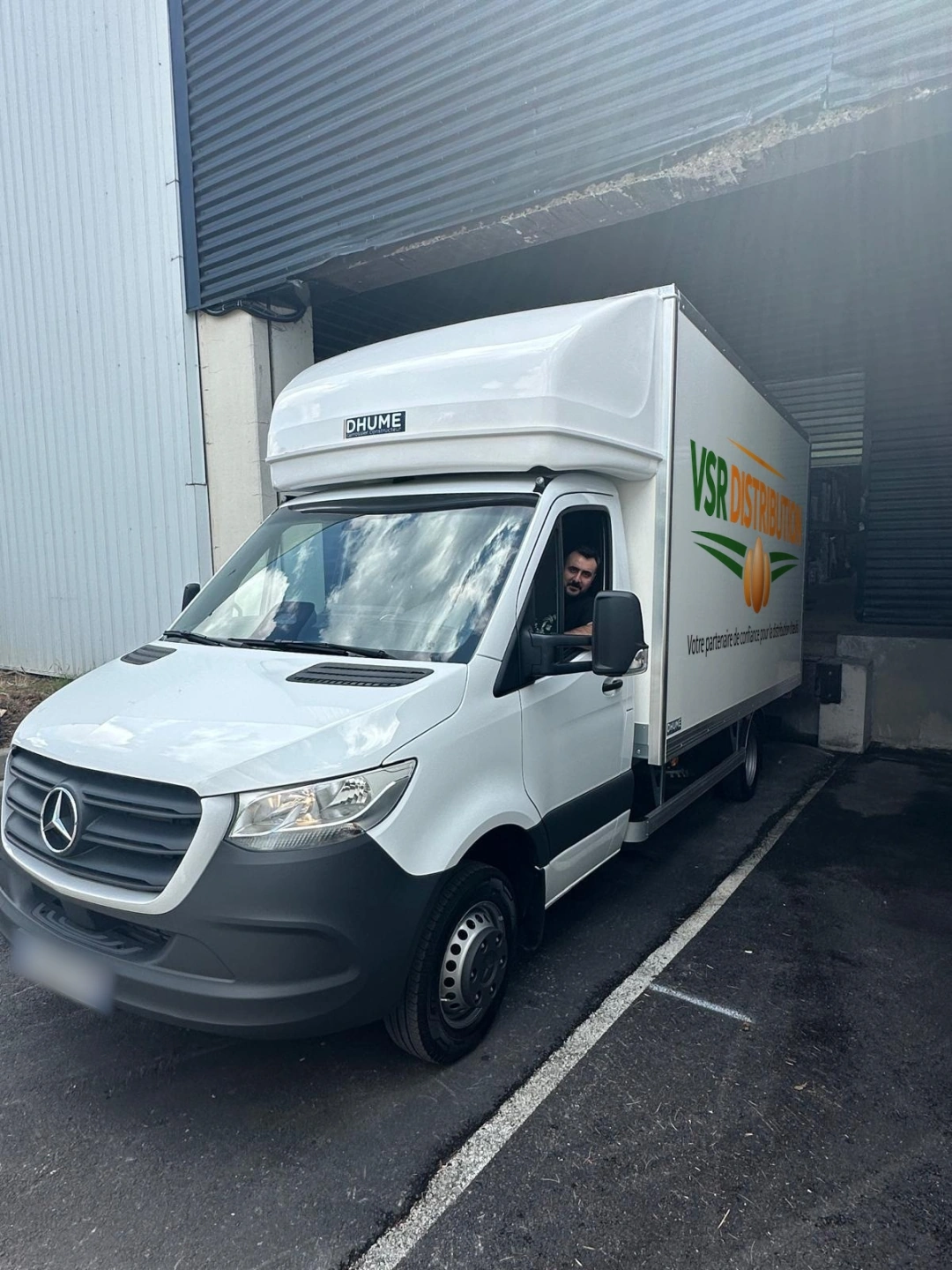 Camion VSR Distribution à quai devant l'entrepôt, chauffeur au volant